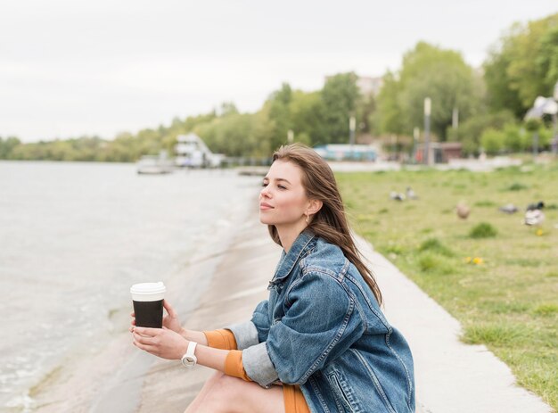 Femmina che gode del caffè in riva al mare