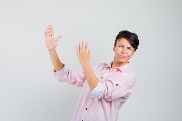 Femmina che mostra il gesto di taglio di karate nella vista frontale della camicia rosa.