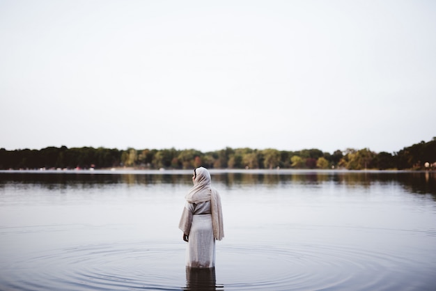 Femmina che porta un abito biblico mentre sta nell'acqua - concetto che pulisce i suoi peccati