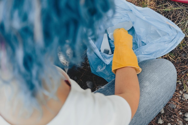 Femmina che raccoglie la spazzatura e mette in un sacchetto di plastica della spazzatura - concetto di inquinamento ambientale