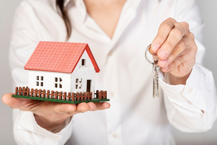 Foto gratuito femmina che tiene una casa e le chiavi del modello del giocattolo