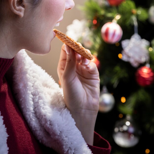 Femmina del primo piano che mangia biscotto a casa