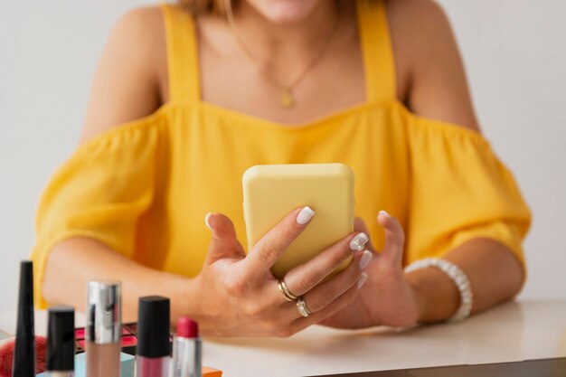 Femmina dell'angolo alto allo scrittorio facendo uso del cellulare