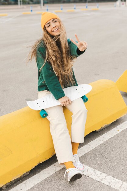Femmina di smiley con skateboard che mostra il segno di pace