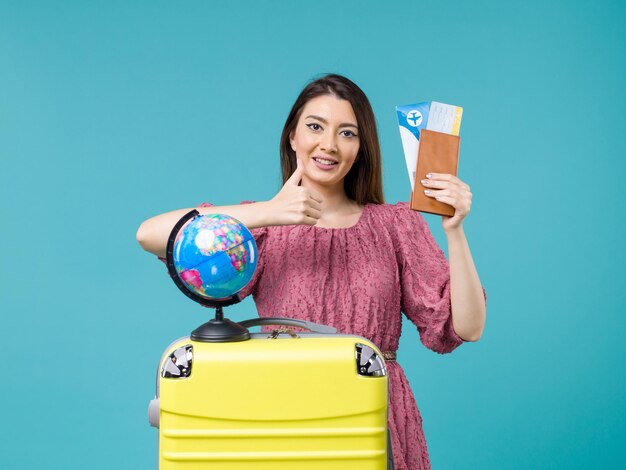 Femmina di vista frontale in vacanza che tiene i biglietti aerei sul viaggio di viaggio della donna di vacanza di viaggio del mare dello scrittorio blu