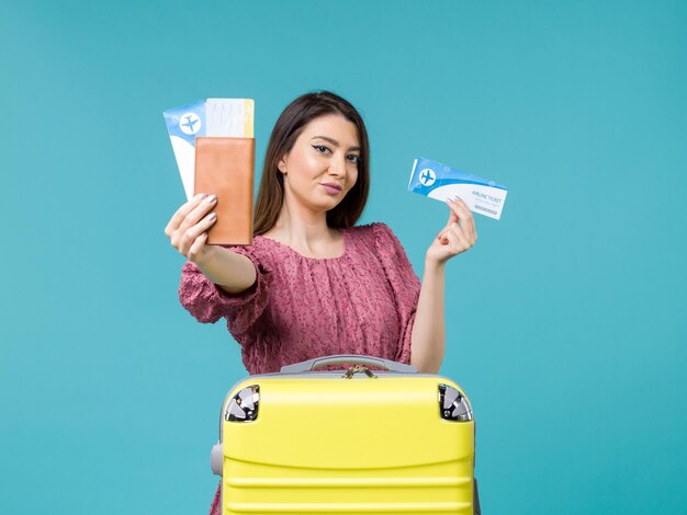 Femmina di vista frontale in vacanza che tiene i suoi biglietti sull'estate di vacanza di viaggio della donna del mare di viaggio della scrivania blu