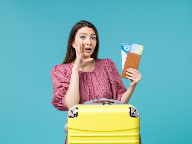 Femmina di vista frontale in vacanza che tiene il suo portafoglio e biglietti su sfondo blu viaggio viaggio donna estate mare vacanza