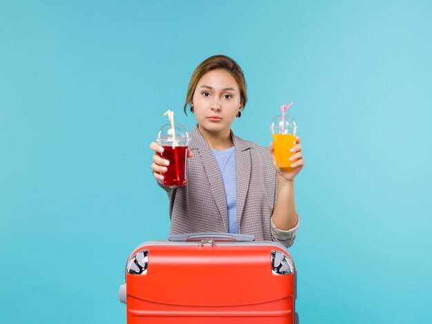 Femmina di vista frontale in vacanza che tiene le bevande fresche sull'aereo di mare di viaggio di viaggio di viaggio di viaggio del pavimento blu