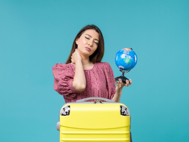 Femmina di vista frontale in vacanza che tiene piccolo globo della terra sull'estate di vacanza di viaggio della donna del mare di viaggio del fondo blu