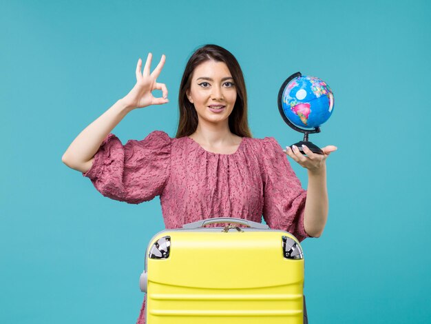 Femmina di vista frontale in vacanza che tiene piccolo globo della terra sulla donna di estate di viaggio di viaggio di vacanza del mare del fondo blu