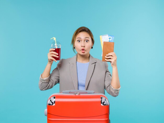 Femmina di vista frontale in vacanza che tiene un bicchiere fresco di succo di frutta e biglietti su sfondo blu viaggio viaggio aereo vacanza viaggio