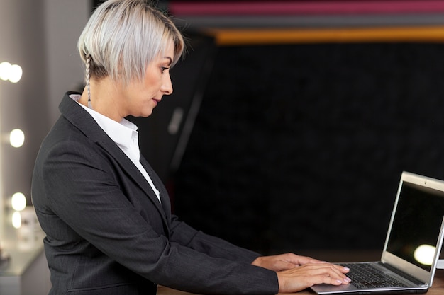 Femmina di vista laterale che lavora al computer portatile