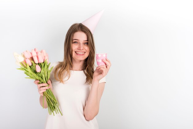 Femmina felice in protezione di compleanno con i fiori