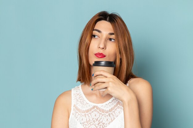 femmina in camicetta bianca e blue jeans che tengono tazza di caffè