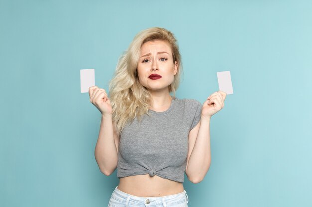 femmina in camicia grigia e blue jeans luminosi che tengono le carte bianche