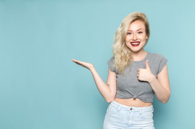 femmina in camicia grigia e blue jeans luminosi in posa con espressione sorridente