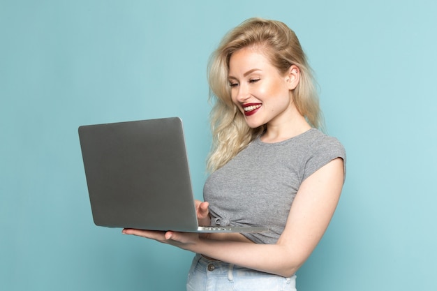 femmina in camicia grigia e jeans blu brillante utilizzando il computer portatile