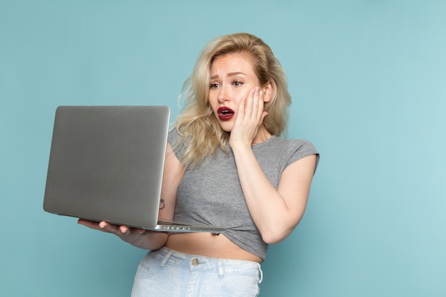 femmina in camicia grigia e jeans blu brillante utilizzando il computer portatile