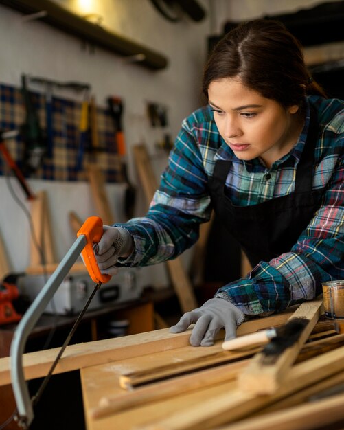 Femmina in officina taglio tavola di legno