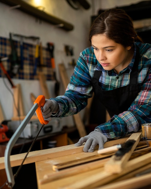 Femmina in officina taglio tavola di legno