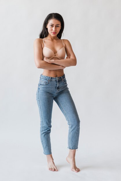 Femmina in reggiseno e denim in piedi con le braccia incrociate