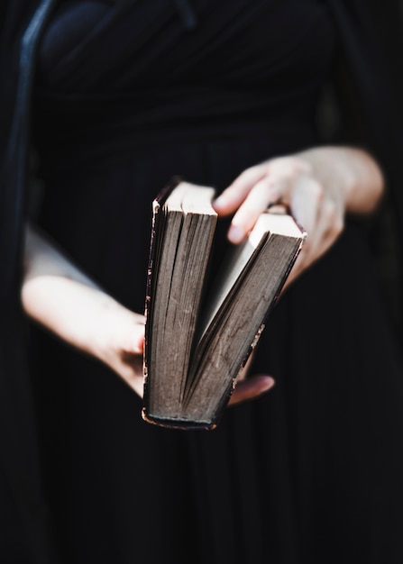 Femmina in vestito nero che tiene libro antico