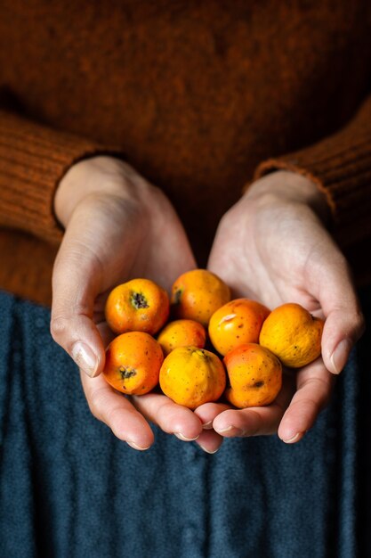 Femmina irriconoscibile che tiene alcuni frutti di tejocotes