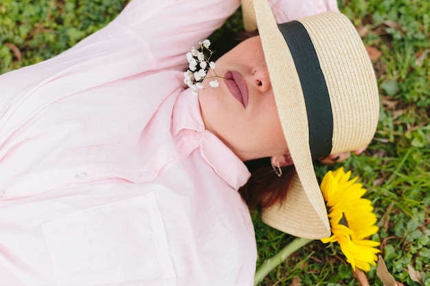 Femmina premurosa in cappello che si trova sull&#39;erba