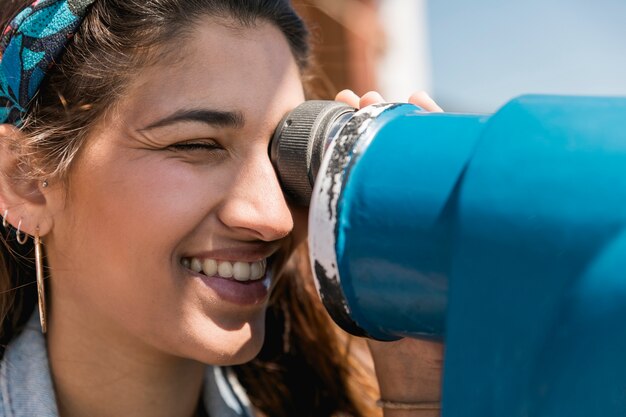 Femmina sorridente che osserva tramite il binocolo