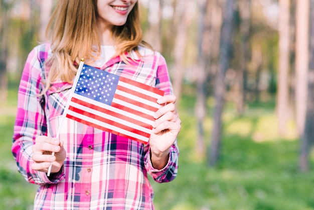 Femmina sorridente con la bandiera americana in mani