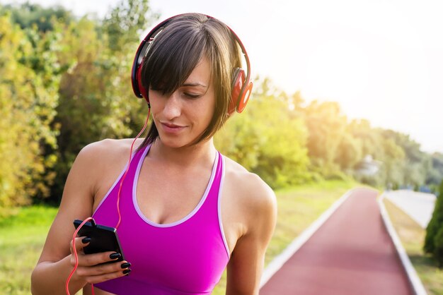 Femmina sportiva che ascolta la musica durante l'allenamento in un parco