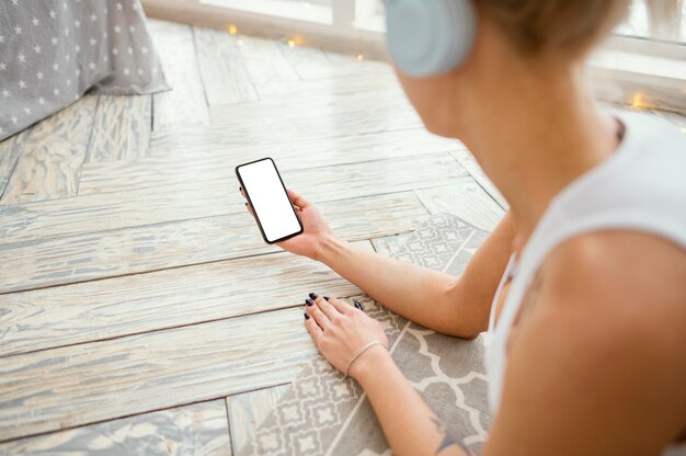 Femmina sulla stuoia con le cuffie utilizzando il telefono