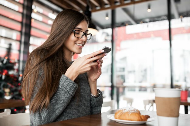 Femmina utilizzando il telefono cellulare cafe