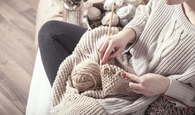 Ferri da maglia in legno d'epoca e filati nelle mani della donna