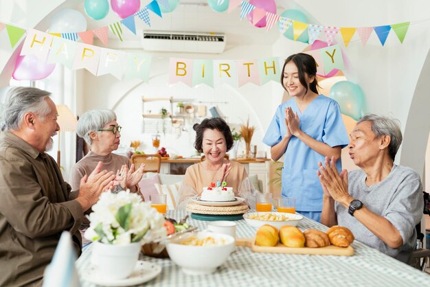 Festa di compleanno all'asilo nido gruppo di donne asiatiche anziano maschio femmina ridere sorriso positivo conversazione saluto in compleanno amico festa presso la casa di cura centro diurno per anziani Compleanno donna anziana