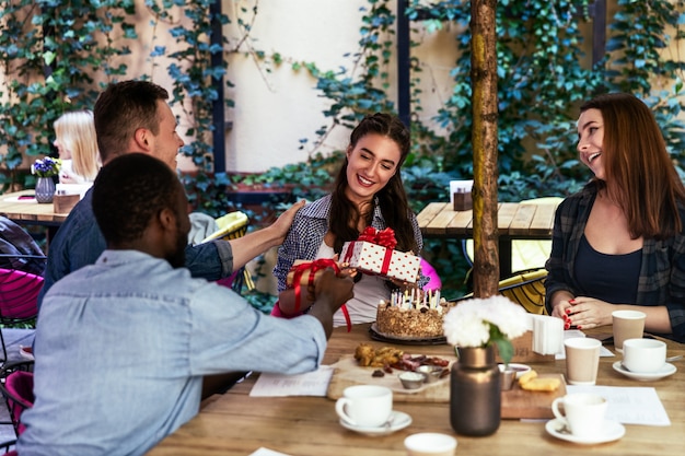 Festa di compleanno di una ragazza sulla terrazza di un caffè con regali dai migliori amici