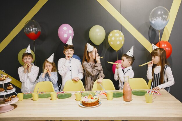 Festa di compleanno divertente per bambini in una stanza decorata. Bambini felici con torta e palloncini.