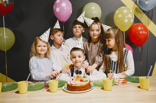 Festa di compleanno divertente per bambini in una stanza decorata. Bambini felici con torta e palloncini.