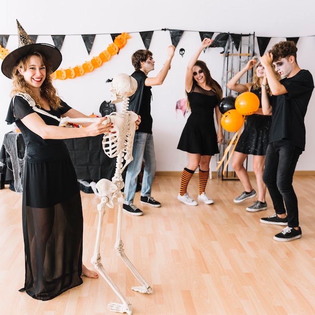 Festa di Halloween adolescente con strega ballando con scheletro