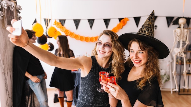 Festa di Halloween con strega e zombie facendo selfie