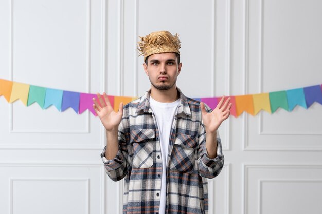 Festa junina bel ragazzo in camicia a quadri con cappello di paglia che celebra il festival molto sorpreso