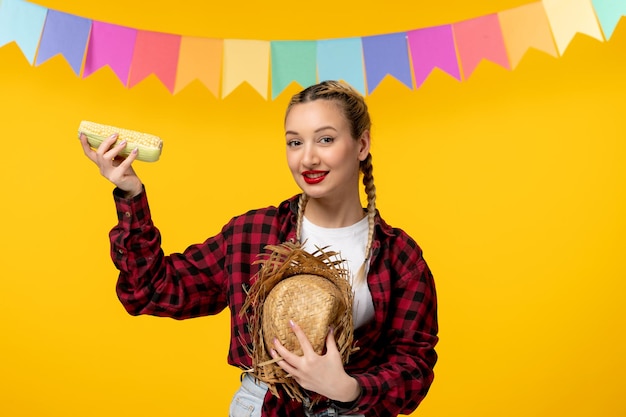 Festa junina bionda ragazza carina in cappello di paglia festival brasiliano con bandiere colorate con mais