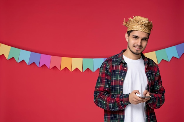 Festa junina felice ragazzo carino che indossa un cappello di paglia che celebra il festival brasiliano al telefono