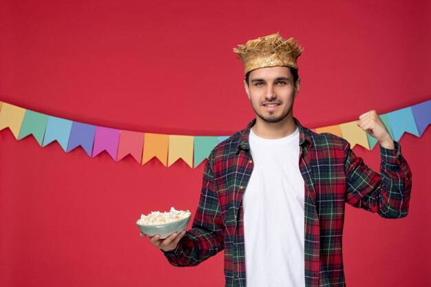 Festa junina felice ragazzo carino che indossa un cappello di paglia che celebra il festival brasiliano con bandiere colorate