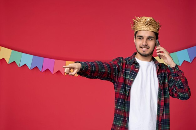 Festa junina felice ragazzo carino che indossa un cappello di paglia che celebra il festival brasiliano facendo telefonata