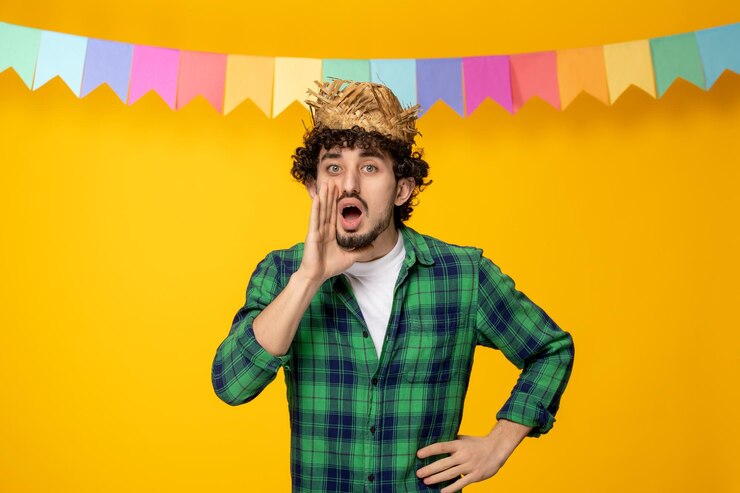 Foto gratuito festa junina giovane ragazzo carino con cappello di paglia e bandiere colorate festival brasiliano che chiama qualcuno