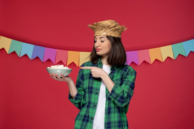 Festa junina in cappello di paglia bruna ragazza carina che celebra il festival brasiliano mangiando popcorn