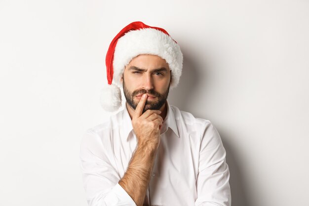 Festa, vacanze invernali e concetto di celebrazione. Uomo serio pensando a Natale e Capodanno, indossando il cappello della Santa
