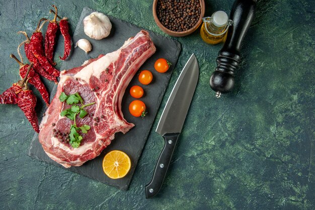 Fetta di carne fresca vista dall'alto con pomodori arancioni su sfondo blu scuro colore cibo carne cucina animale pollo mucca macellaio