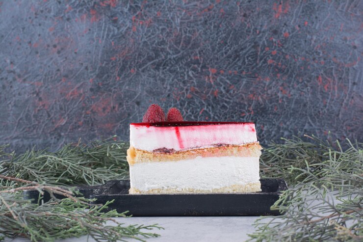 Foto gratuito fetta di cheesecake su tavola nera con ramo di pino. foto di alta qualità